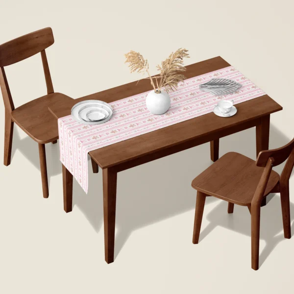 Pink gingerbread Christmas table runner on a walnut dining table with two wooden chairs