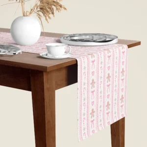 Pink gingerbread Christmas table runner hanging over the end of a walnut dining table, close-up