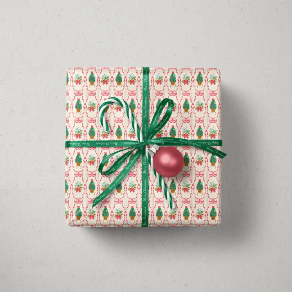Top view of a gift in pink ribbon frame paper with a ribbon, candy canes and a bauble