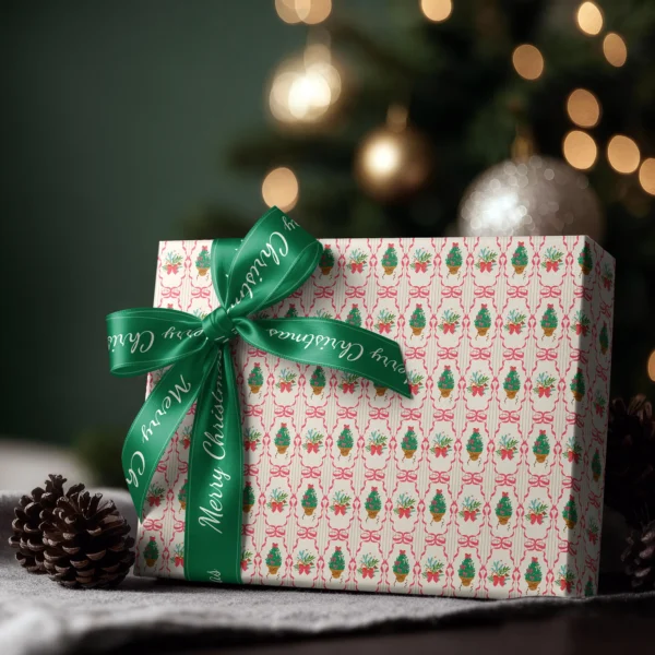 Box wrapped in pink ribbon frame paper with a satin ribbon bow, Christmas tree lights behind
