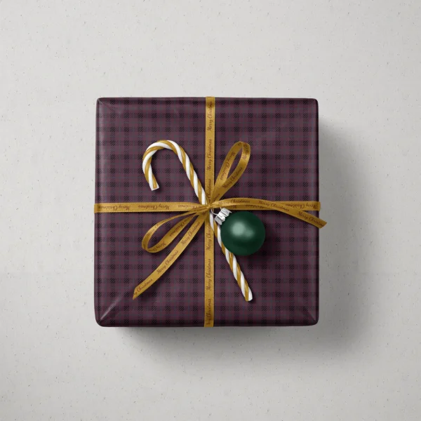 Top view of a gift in plum and black plaid paper with a ribbon, striped candy and a bauble