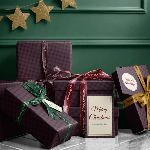 Stack of presents in plum and black plaid paper with ribbons and a greeting card by a dark green wall