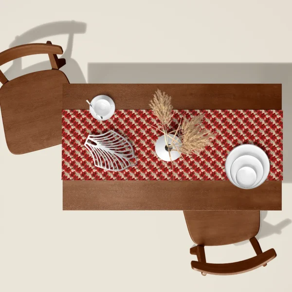 Red poinsettia Christmas table runner seen from above on a walnut table with white dishes and dried pampas