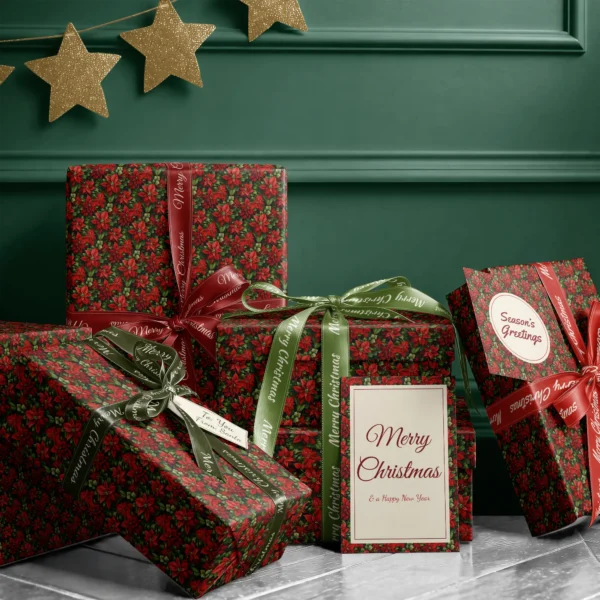 Stack of presents in dark green poinsettia paper with ribbons and a Merry Christmas card by a dark green wall