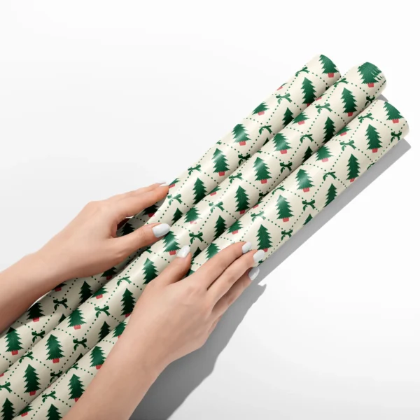 Hands smoothing three rolls of potted tree diamond wrapping paper on a white table
