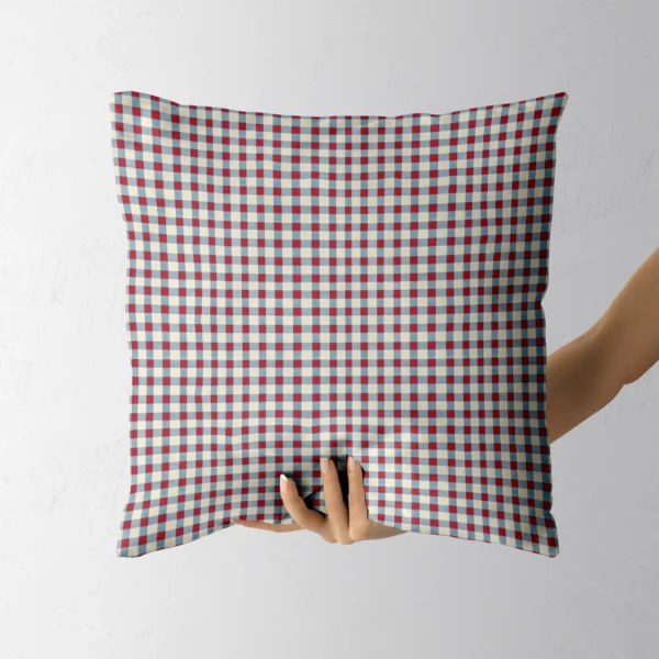 Hand holding the square cream and blue gingham check pillow