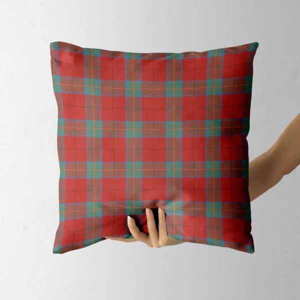 Hand holding the coral and teal plaid throw pillow