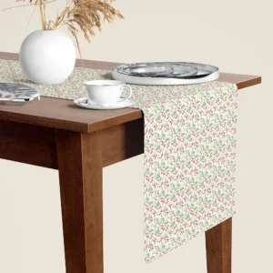 Red berry sprig Christmas table runner hanging over the end of a walnut dining table, close-up