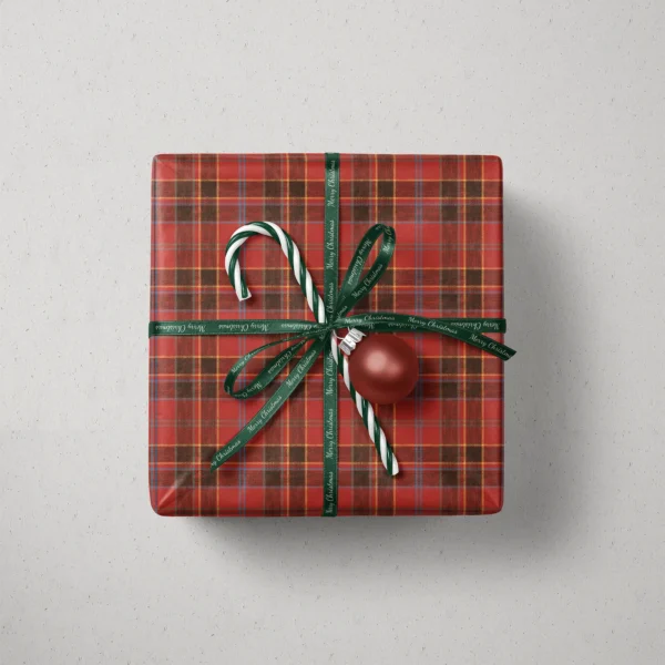 Top view of a gift in red and black block plaid paper with a ribbon, candy canes and a bauble