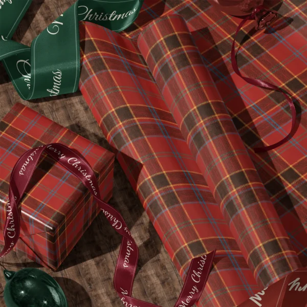 Rolls of red and black block plaid gift wrap and a wrapped box with satin ribbons on a wooden floor