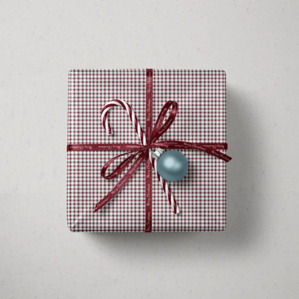 Top view of a gift in red and blue gingham paper with a ribbon, a candy cane and a bauble