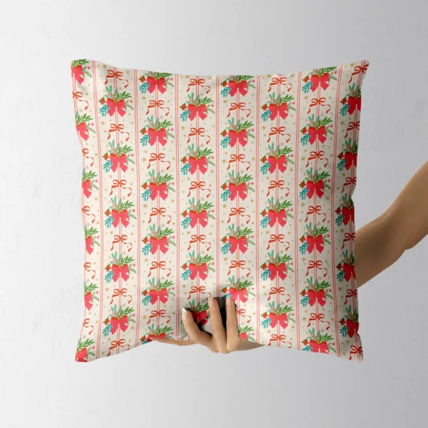 A hand holding the cream throw pillow with red bow and pine posies