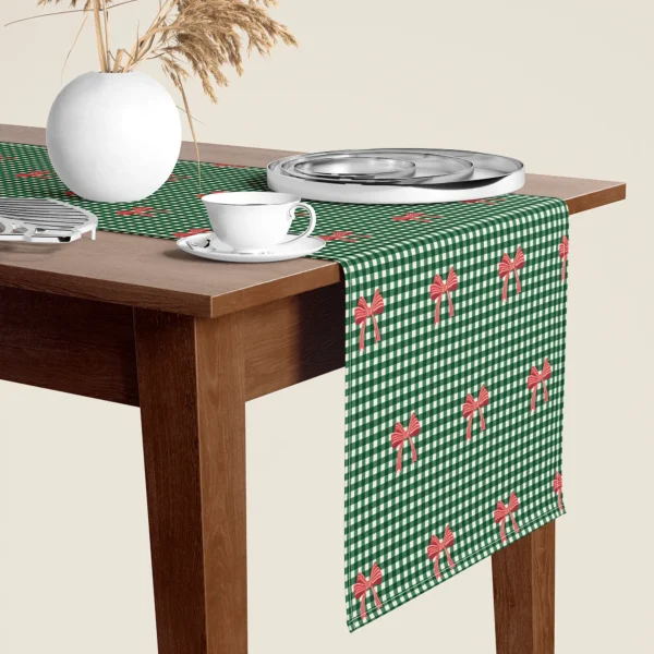 Red bow gingham Christmas table runner hanging over the end of a walnut dining table, close-up