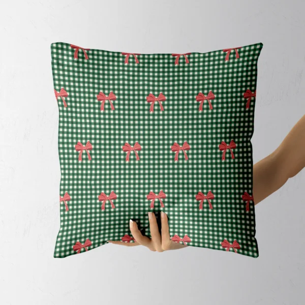 Hand holding the green micro gingham throw pillow with little red bows
