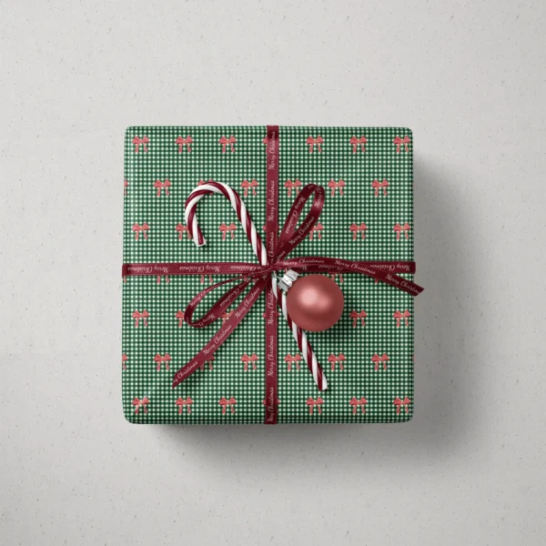 Top view of a gift in red bow gingham paper with a ribbon, candy canes and a bauble