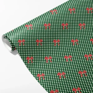 Roll of tiny green and cream gingham wrapping paper with small red bows in staggered rows, partly unrolled on white