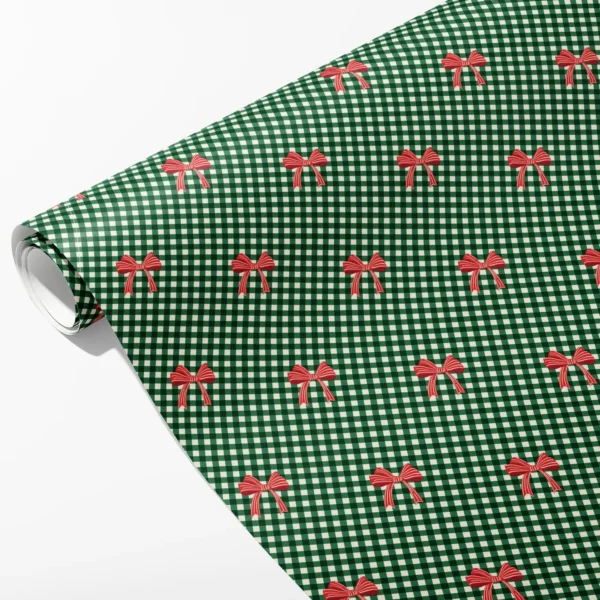 Roll of tiny green and cream gingham wrapping paper with small red bows in staggered rows, partly unrolled on white