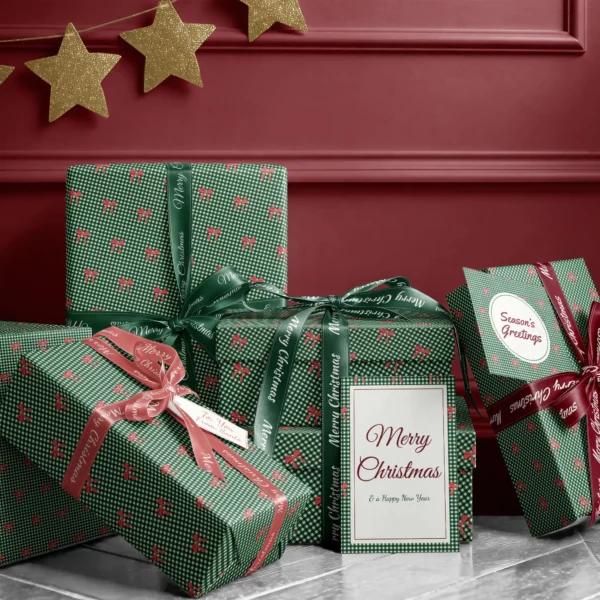 Stack of presents in red bow gingham paper with ribbons and a Merry Christmas card by a burgundy wall