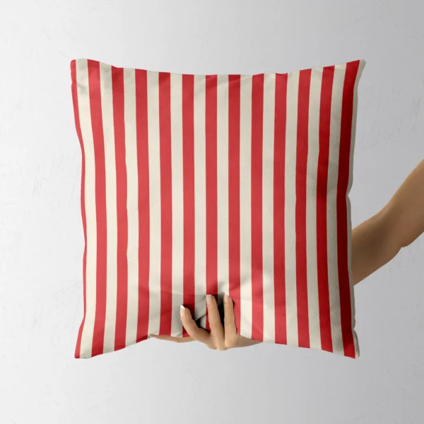 Hand holding the red and cream striped throw pillow