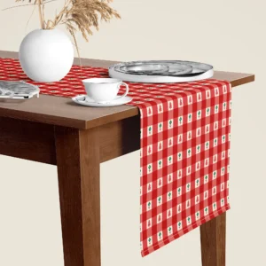 Red gingham tiny tree Christmas table runner hanging over the end of a walnut dining table, close-up