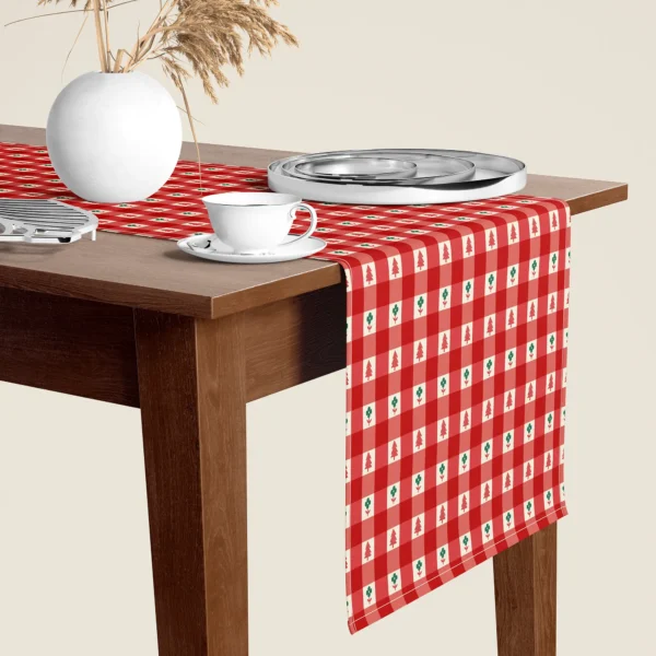 Red gingham tiny tree Christmas table runner hanging over the end of a walnut dining table, close-up