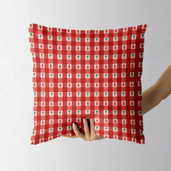 Hand holding the red check pillow with little trees and green flowers