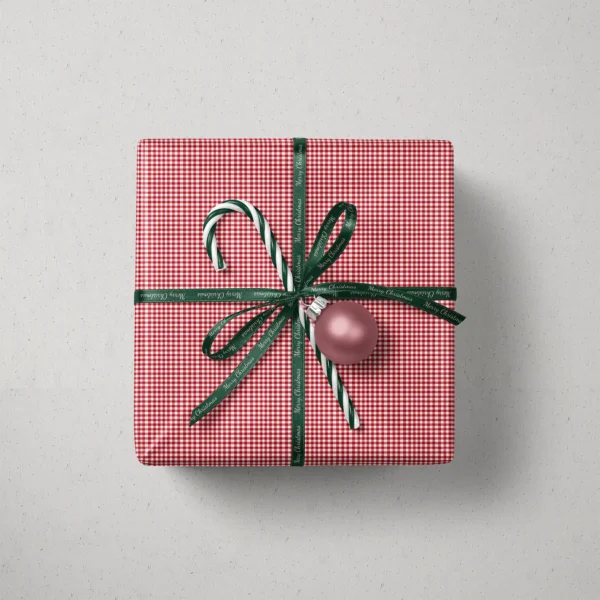 Top view of a gift in red gingham paper with a ribbon, a candy cane and a bauble