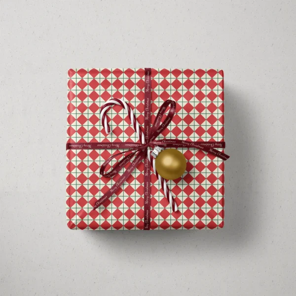 Top view of a gift in red harlequin paper with a ribbon, candy canes and a bauble