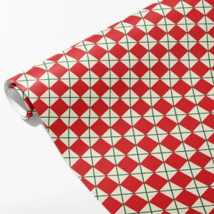 Roll of cream wrapping paper with red diamonds framed by a fine green lattice, partly unrolled on white
