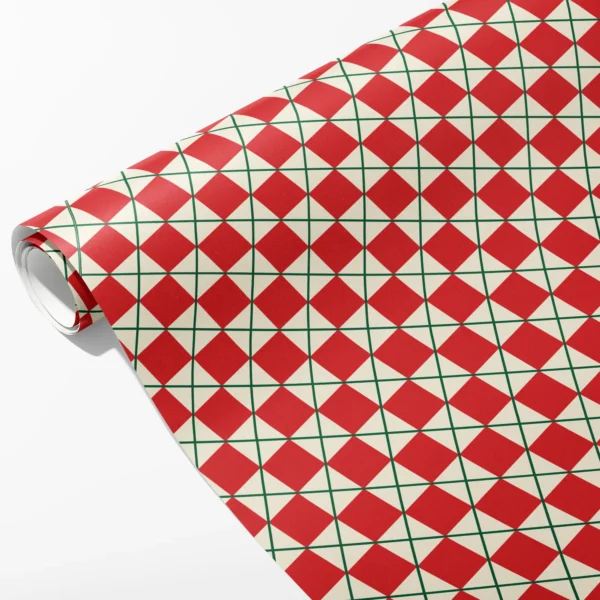 Roll of cream wrapping paper with red diamonds framed by a fine green lattice, partly unrolled on white