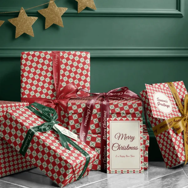Stack of presents in red harlequin paper with ribbons and a Merry Christmas card by a dark green wall