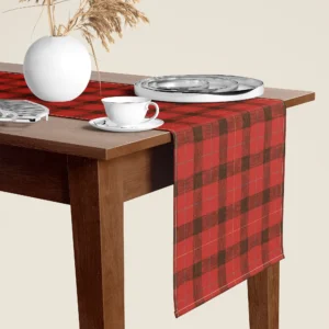 Red lumberjack check Christmas table runner hanging over the end of a walnut dining table, close-up