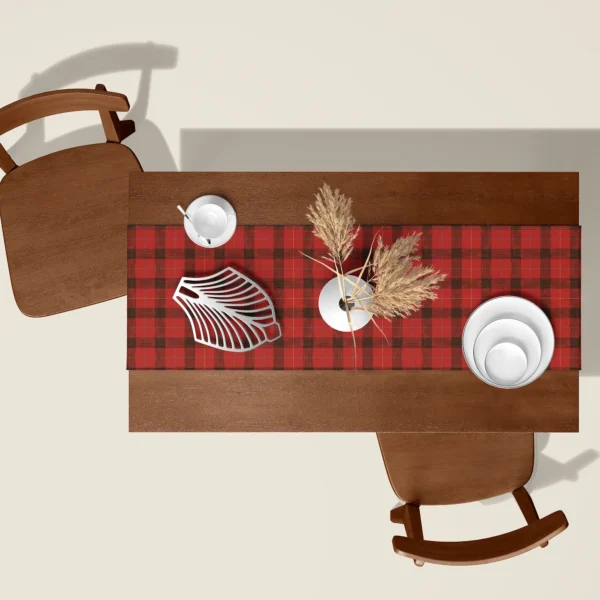 Red lumberjack check Christmas table runner seen from above on a walnut table with white dishes and dried pampas