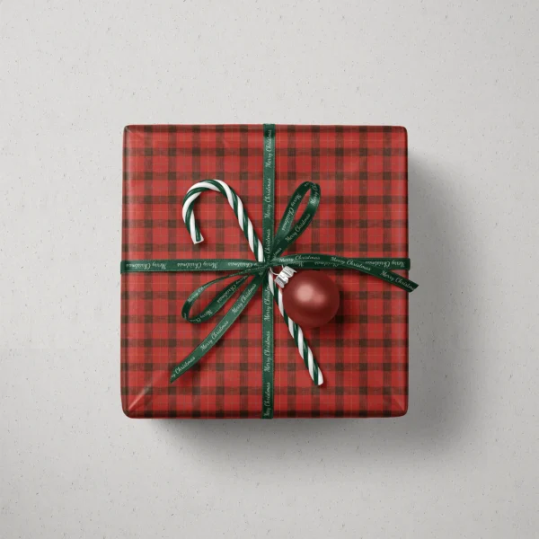 Top view of a gift in red lumberjack check paper with a ribbon, candy canes and a bauble