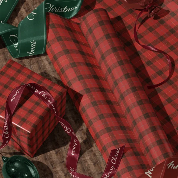 Rolls of red lumberjack check gift wrap and a wrapped box with satin ribbons on a wooden floor