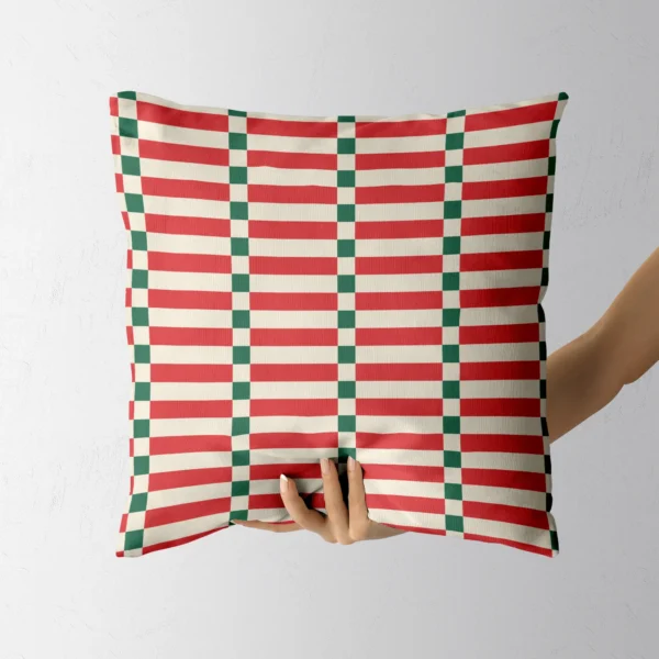 A hand holding the red and cream ladder stripe throw pillow