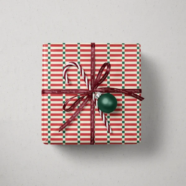 Top view of a gift in red stripe ladder paper with a ribbon, candy canes and a bauble