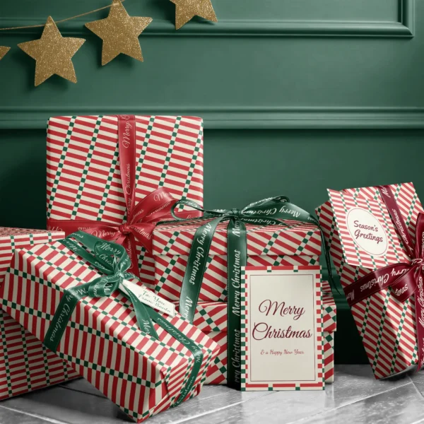 Stack of presents in red stripe ladder paper with ribbons and a Merry Christmas card by a dark green wall