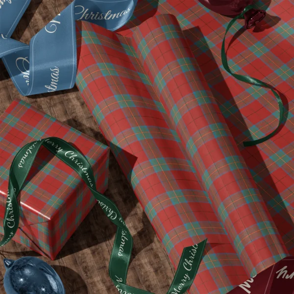 Rolls of red and teal windowpane plaid gift wrap and a wrapped box with satin ribbons on a wooden floor