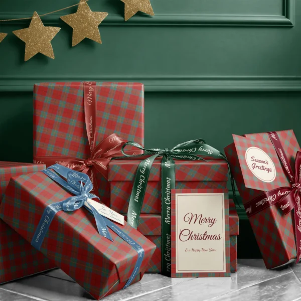 Stack of presents in red and teal windowpane plaid paper with ribbons and a Merry Christmas card by a dark green wall