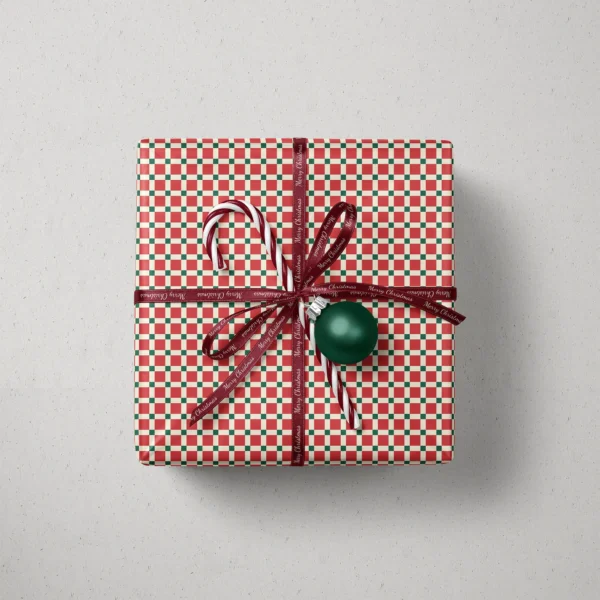 Top view of a gift in red tile check paper with a ribbon, candy canes and a bauble