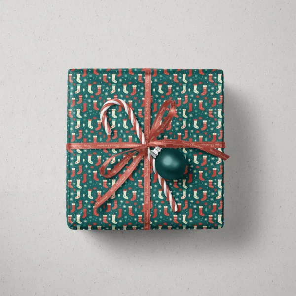 Top view of a gift in teal Christmas stocking paper with a ribbon, a candy cane and a bauble
