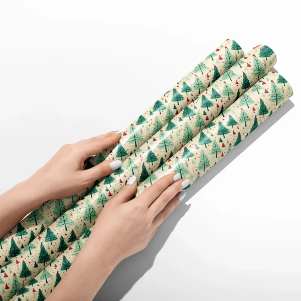Hands smoothing three rolls of cream retro green tree wrapping paper on a white table