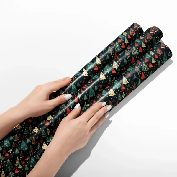 Hands smoothing three rolls of starry navy tree wrapping paper on a white table