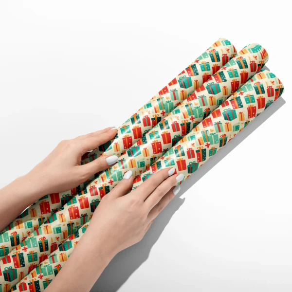 Hands smoothing three rolls of retro present wrapping paper on a white table