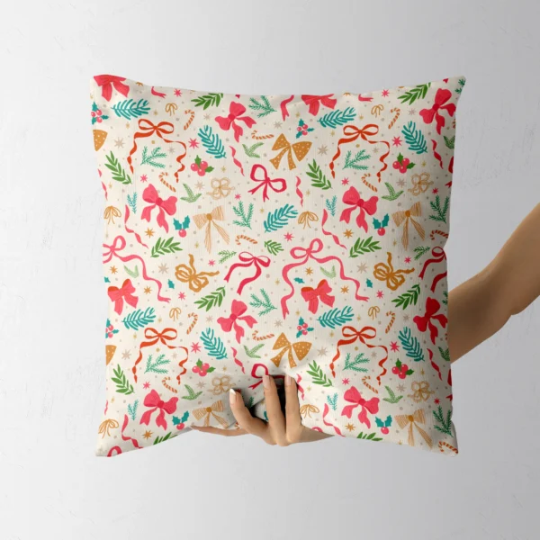 Hand holding the cream throw pillow with pink bows and pine sprigs