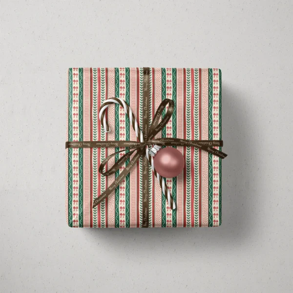 Top view of a gift in ribbon stripe paper with a ribbon, candy canes and a bauble