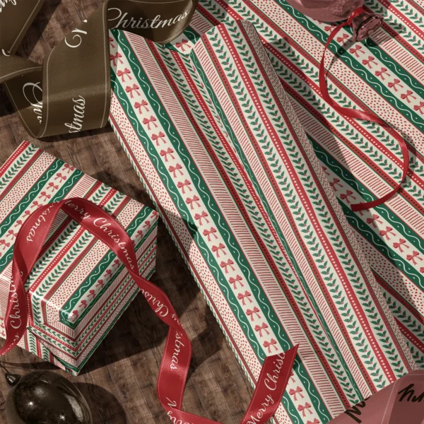 Rolls of ribbon stripe gift wrap and a wrapped box with satin ribbons on a wooden floor
