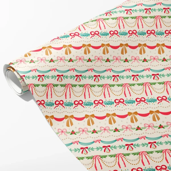 Roll of cream wrapping paper with horizontal bands of pink and gold bows, bunting and garland, partly unrolled on white