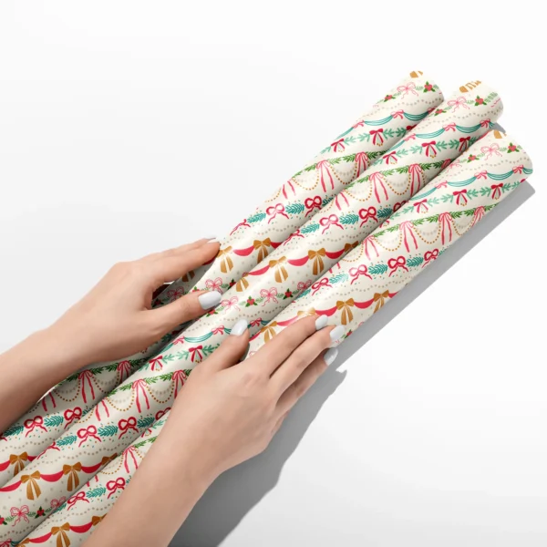 Hands smoothing three rolls of ribbon swag wrapping paper on a white table